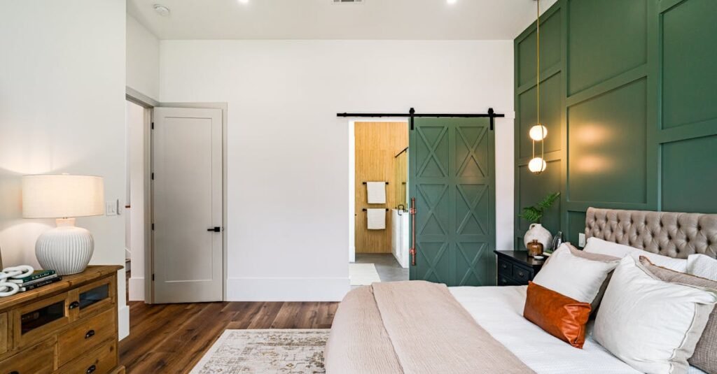 Beautiful modern bedroom with green accent wall and barn door leading to the bathroom.